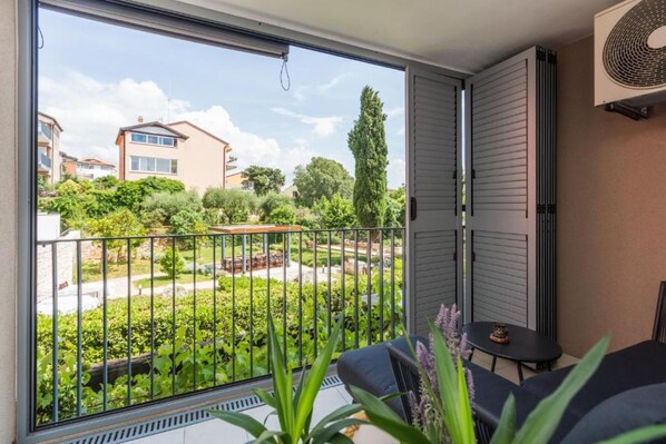 A balcony with a view of a garden and neighboring houses.