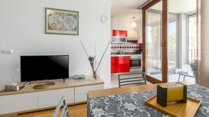 Eine moderne Küche mit roten Schränken, einem Flachbildfernseher und einem Essbereich mit Tisch und Stühlen.