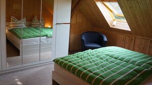 Un dormitorio con cama tipo loft, una silla y un tragaluz.