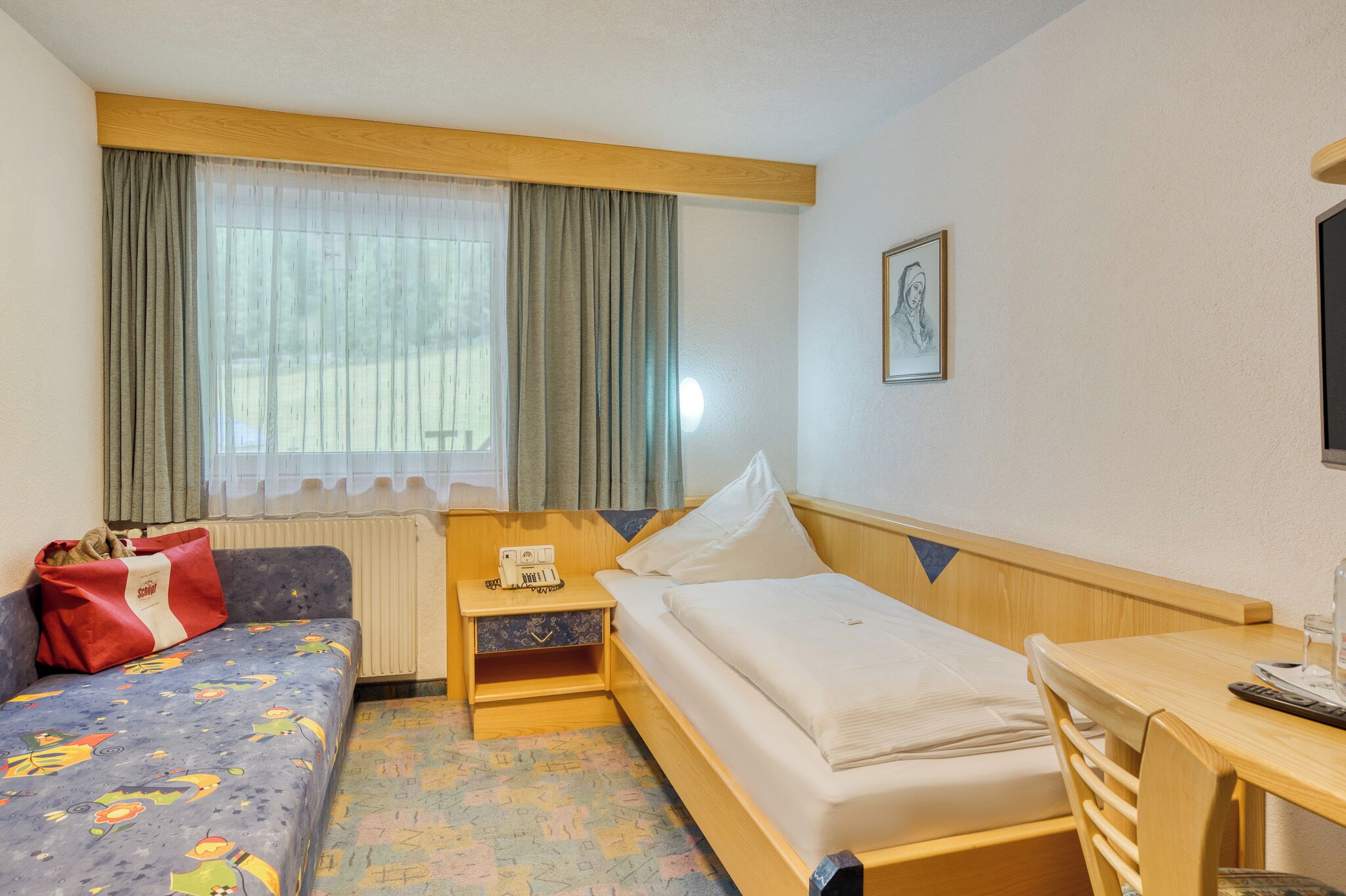 Une chambre d’hôtel avec un lit, un canapé, un bureau et une fenêtre avec des rideaux.