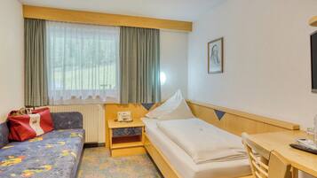 Une chambre d’hôtel avec un lit, un canapé, un bureau et une fenêtre avec des rideaux.