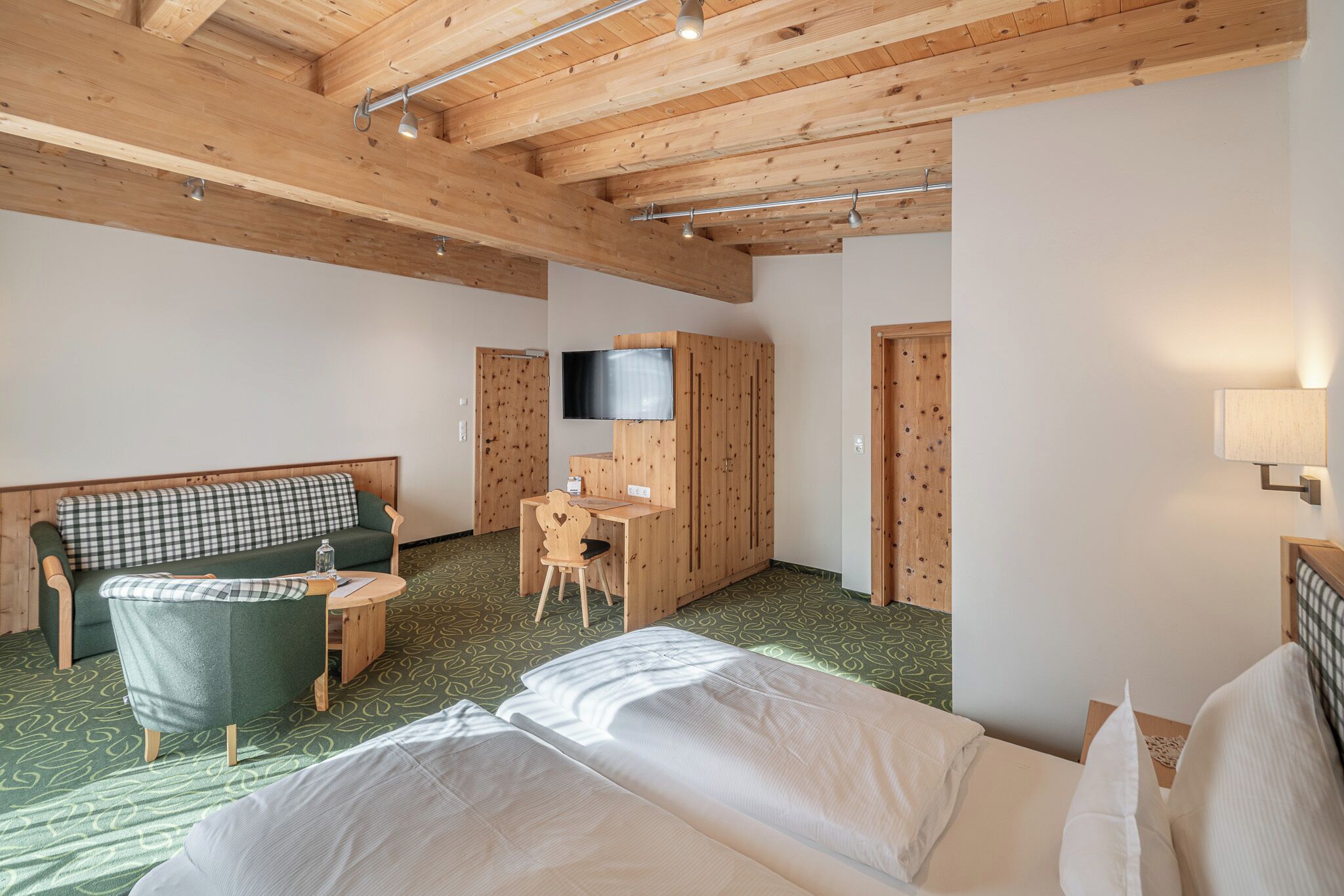 A room with a bed, a desk, a television, and a couch.