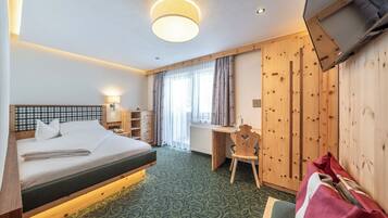 Ein Hotelzimmer mit einem Bett, einem Schreibtisch, einem Sessel, einer Heizung und einem Fernseher.