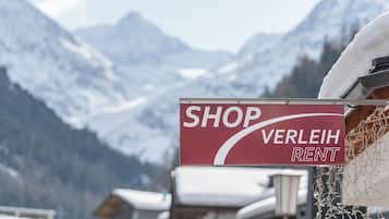 A sign for a shop named 'VERLEIH RENT' against a backdrop of snow-covered mountains.