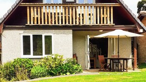 Una casa a due piani con un balcone, un patio con tavolo e sedie, e un prato curato.