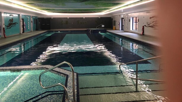 Una piscina interna con un affresco sul soffitto, acqua cristallina e pareti piastrellate.