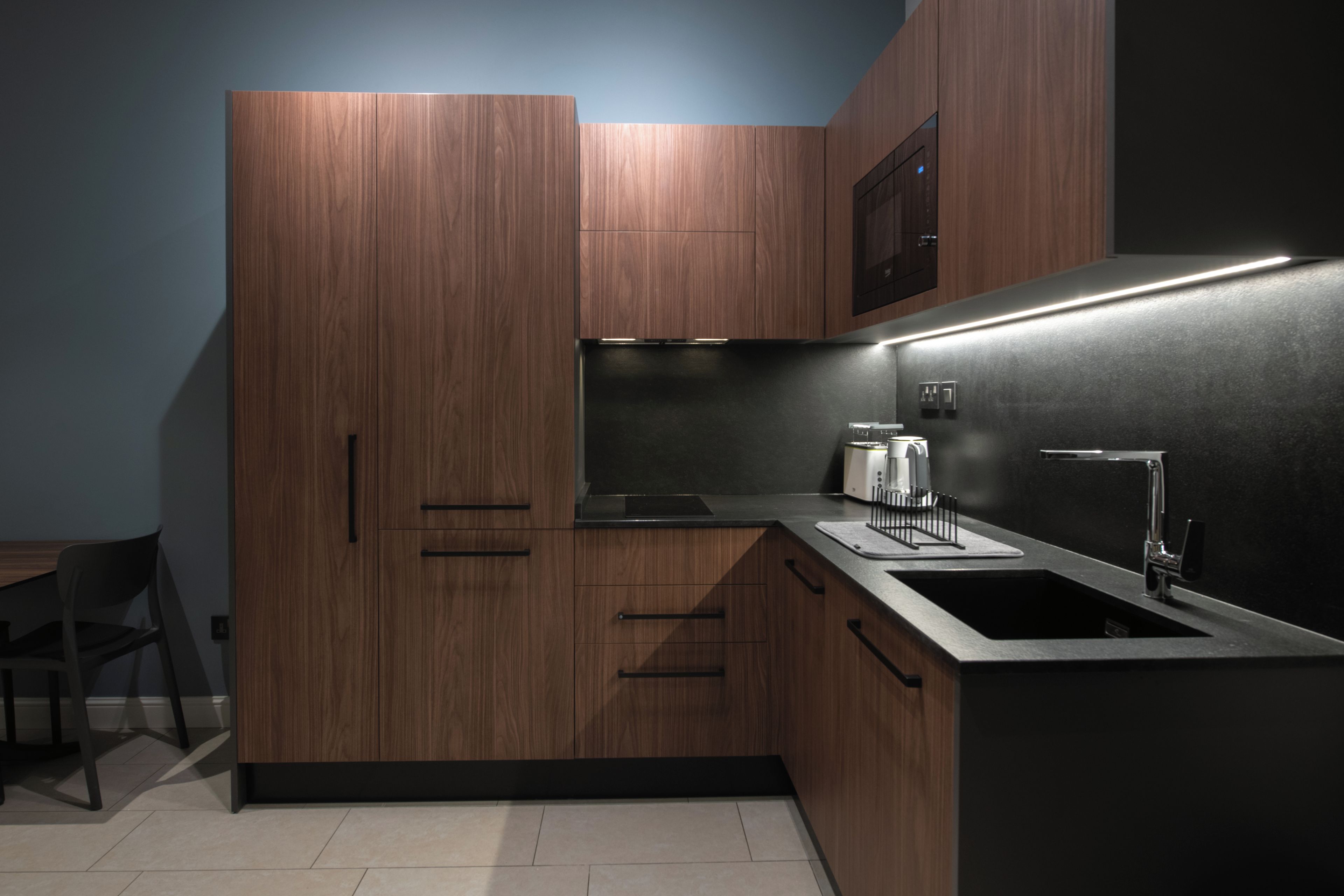 A modern kitchen with wooden cabinets, a stainless steel sink, and a built-in oven.