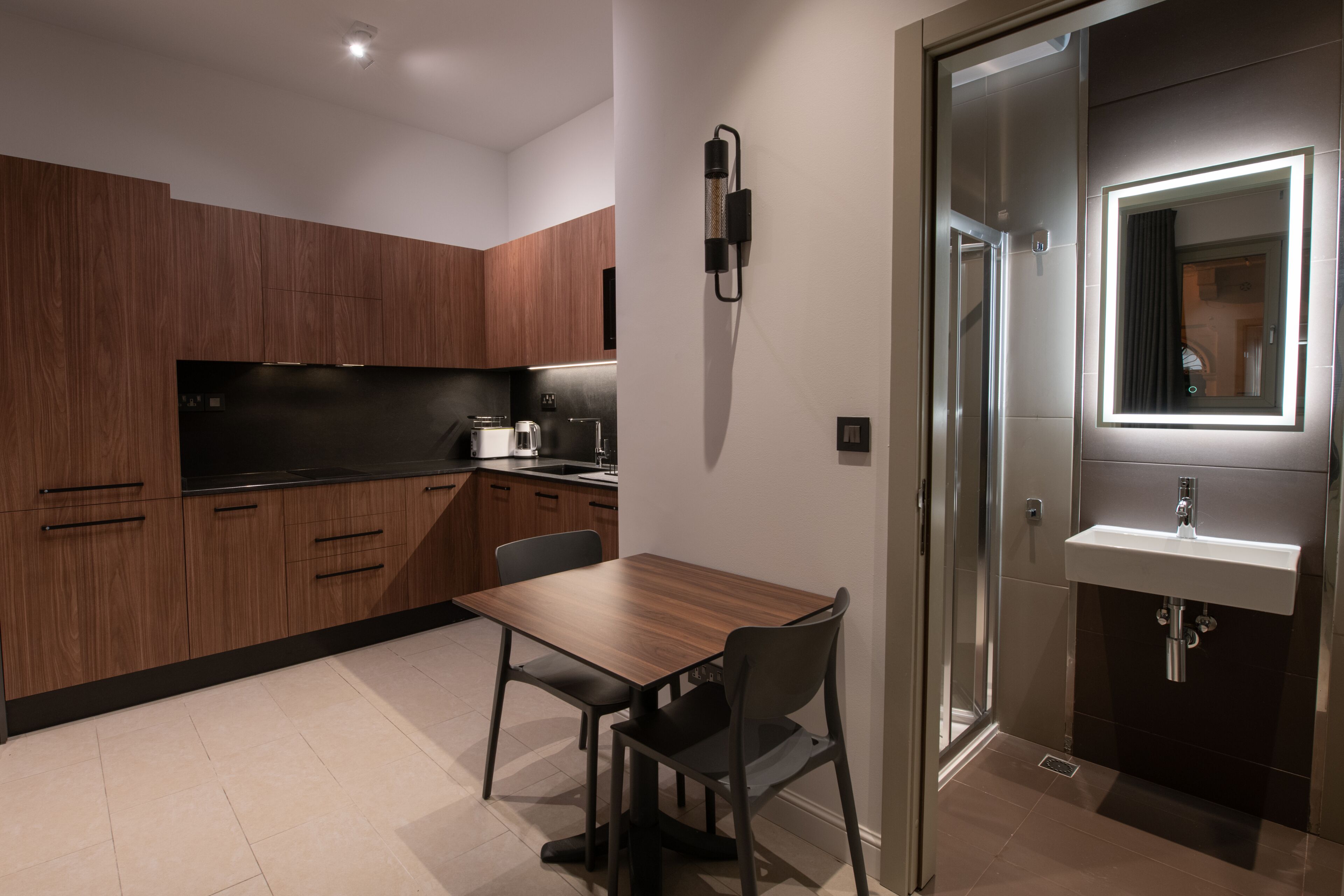 Una cocina moderna con armarios de madera, encimera negra y un comedor con mesa y sillas.