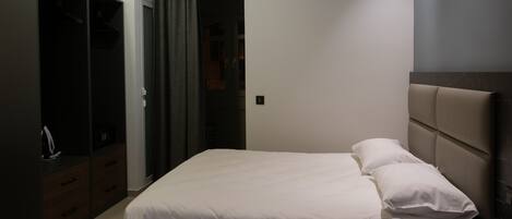 A bedroom with a bed, a wardrobe, and an air conditioning unit.