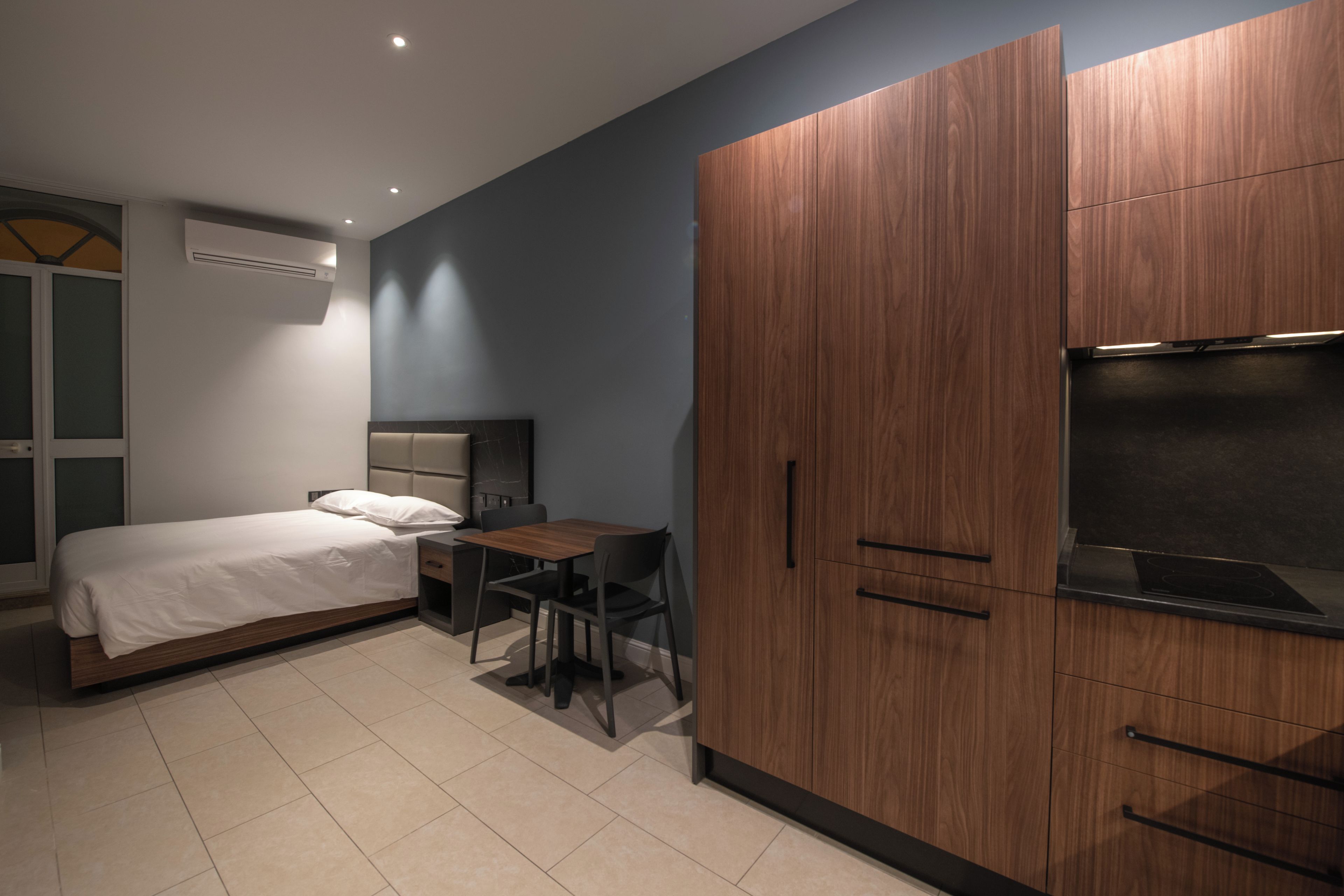 A modern bedroom with a bed, a desk, and a wardrobe.