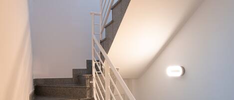 Una escalera de granito con barandales blancos que conduce a un piso superior.