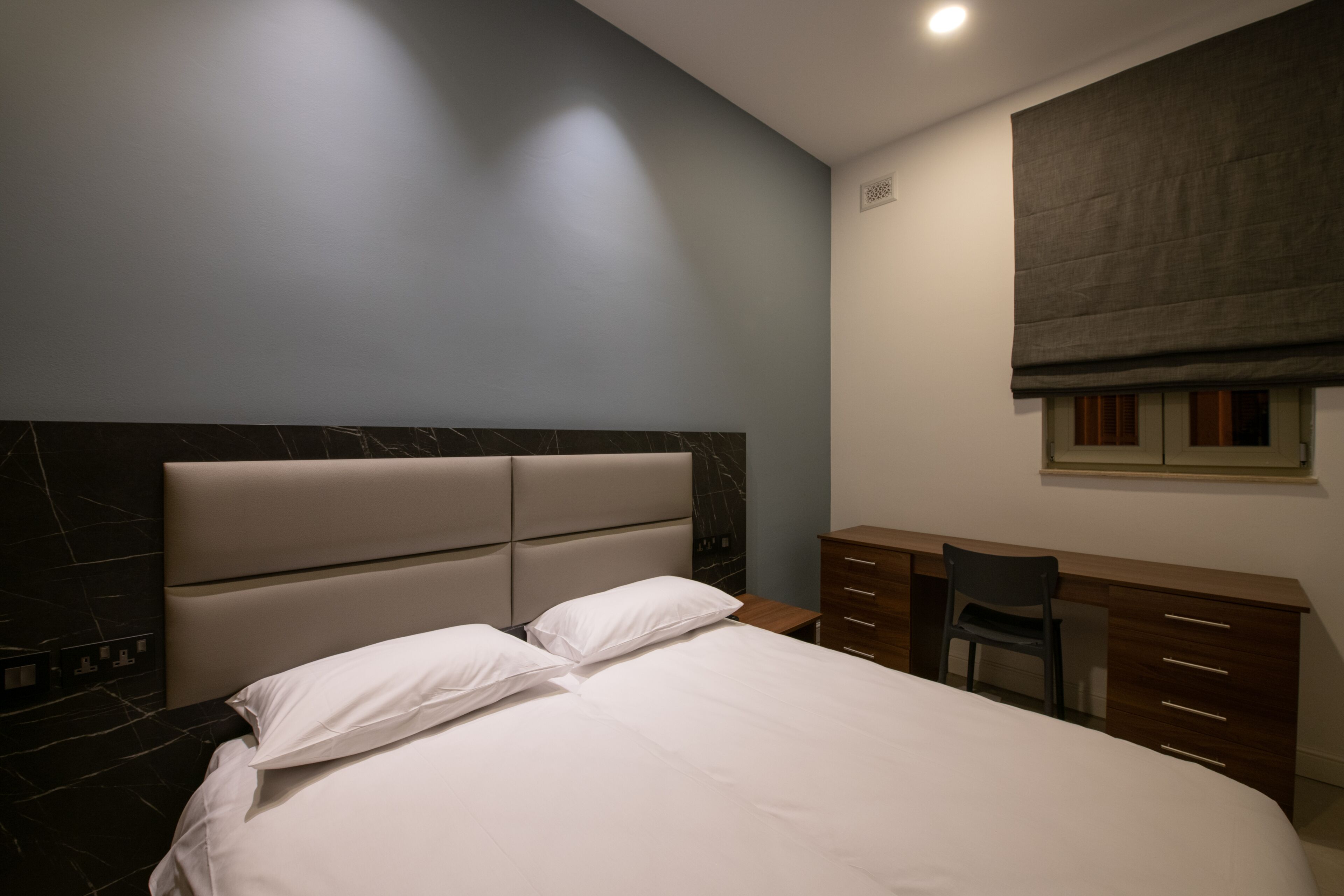 A bedroom with a bed, a desk, and a chair.