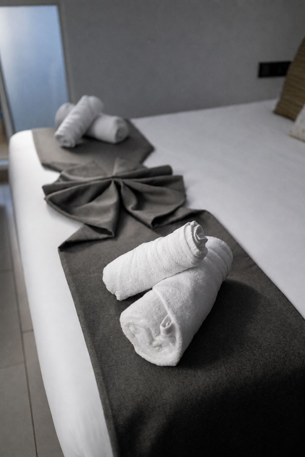 Ein Bett mit ordentlich gefalteten Handtüchern und einer dekorativen Schleife am Kopfteil.