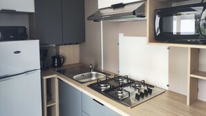 Een kleine keuken met een ingebouwde gasplaat, een magnetron en een koelkast.