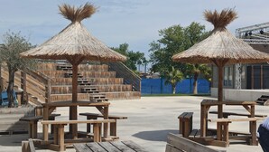 Houten constructies met rieten daken en bankjes, waarschijnlijk onderdeel van een resort of park.