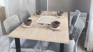 Een eetruimte met een houten tafel, vier stoelen en aan beide zijden twee kommen.