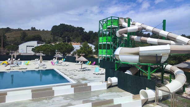 Een waterpark met een zwembad, glijbanen en ligbedden.