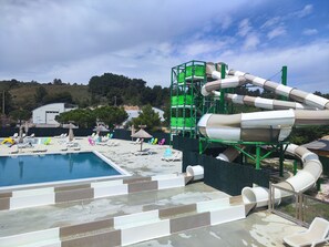 Parque acuático con piscina, toboganes y sillas de descanso.