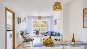 Un coin repas avec une table dressée pour deux personnes, une bouteille de vin et un saladier de fruits.