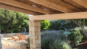 An outdoor patio with a wooden table and chairs, surrounded by stone walls and greenery. - Villa Capperi - Very Private Villa with Pool for Full Relax (Puglia)