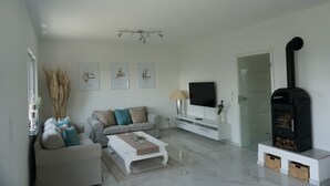 A modern living room with a sofa, coffee table, TV, and a wood-burning stove. - Ferienhaus mit Wunderschöner Aussicht in Zentraler Lage (Weitersburg)