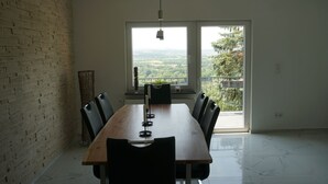 A dining area with a long wooden table, black chairs, and a hanging light fixture. - Ferienhaus mit Wunderschöner Aussicht in Zentraler Lage (Weitersburg)