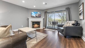 Un salon moderne avec une cheminée, un canapé, une table basse et un téléviseur.