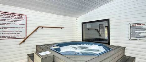 A spa area with a hot tub, wooden steps, and a sign listing rules.