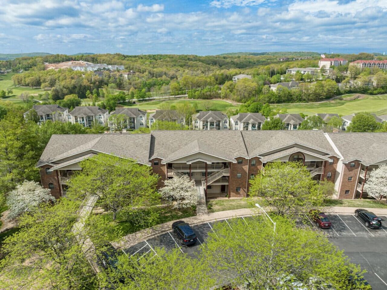 A multi-story hotel with a brick facade, a central courtyard, and a parking lot.