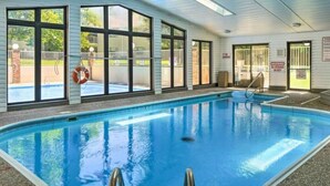 Une piscine intérieure avec des parois en verre transparent, une bouée de sauvetage et un panneau d’avertissement.