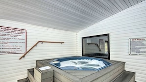Area benessere con vasca idromassaggio, scalini in legno e cartello con le regole per l'utilizzo della piscina.