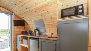 Une cuisine compacte avec des murs en bois, un four à micro-ondes, un évier et un petit réfrigérateur.