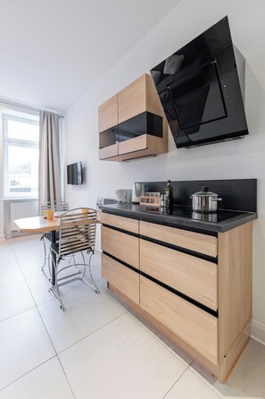 A modern kitchen with a built-in stove, wooden cabinets, and a dining area with a table and chairs.
