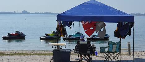A beach with a blue tent, kayaks, and a table.