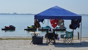 Ein Strand mit einem blauen Zelt, Kajaks und einem Tisch.
