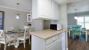 A kitchen with white cabinetry, a microwave, and a dining area with chairs and a table. - BOOK NOW & SAVE!! CLOSE TO IMG!  Base Rent has been REDUCED by 20 percent!  West Bradenton Pool Home |The Tranquila House | Heated Pool | Near Anna Maria Island | Sleeps 6 (Bradenton)