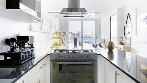 Eine moderne Küche mit Gasherd, einer Edelstahl-Dunstabzugshaube und einem großen Fenster mit Blick auf die Stadt.