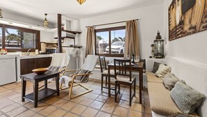 Un'ampia zona giorno con tavolo da pranzo, sedie, divano e cucina sullo sfondo.