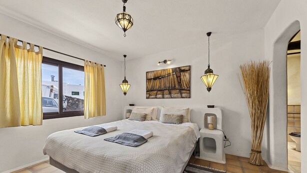 Una camera da letto con un letto grande, due comodini, un'opera d'arte appesa al muro e una finestra con tende.