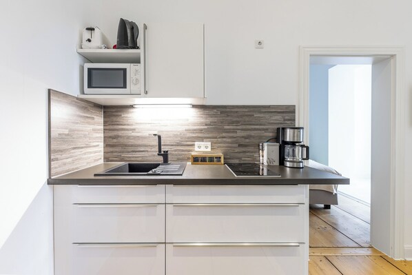 A modern kitchen with a built-in microwave, a coffee maker, and a small oven.