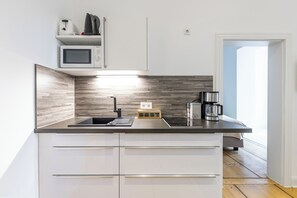A modern kitchen with a built-in microwave, a coffee maker, and a small oven.