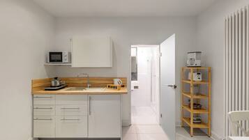 Eine moderne Küche mit weißen Schränken, einer Holz Arbeitsplatte und einer eingebauten Mikrowelle.