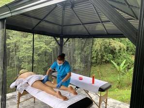 A massage therapy session in a covered outdoor area with a view of a forested landscape. - Ecohotel Portillo de San Bernardo  (Vergara)
