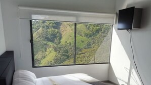 A bedroom with a large window offering a view of a green landscape. - Ecohotel Portillo de San Bernardo  (Vergara)