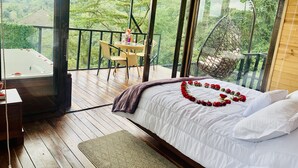 A bedroom with a bed, a wooden floor, a balcony with a table and chairs, and a hot tub. - Ecohotel Portillo de San Bernardo  (Vergara)