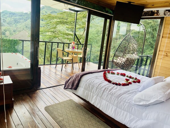 A bedroom with a bed, a wooden floor, a balcony with a table and chairs, and a hot tub. - Ecohotel Portillo de San Bernardo  (Vergara)