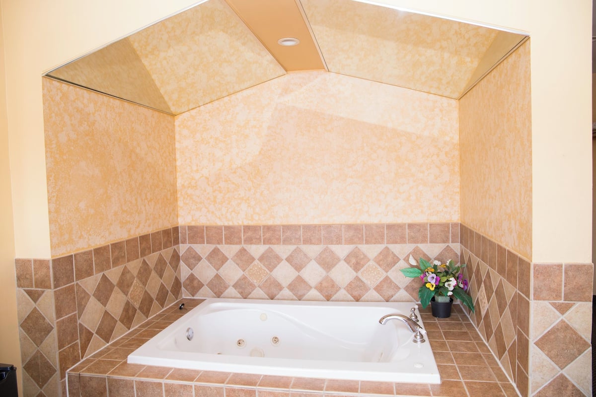 A bathroom with a freestanding bathtub, tiled walls, and a potted plant.