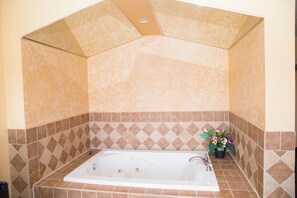 A bathroom with a freestanding bathtub, tiled walls, and a potted plant.