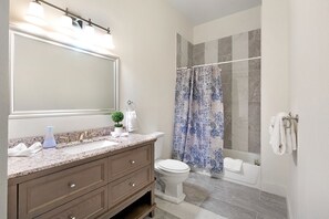 Un baño con un espejo grande, un lavabo, un inodoro y una zona de ducha.