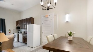 A modern kitchen with dark wooden cabinets, a white refrigerator, and a dining area with a wooden table and chairs. - Chic and Roomy Urban Getaway in New Orleans (New Orleans)